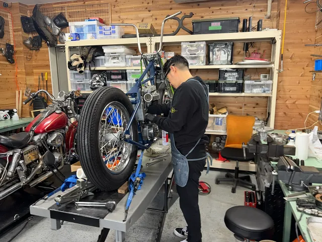 リフトに載せた1957年式Triumph TR6の車体と、クラッチ周りの組み付け作業