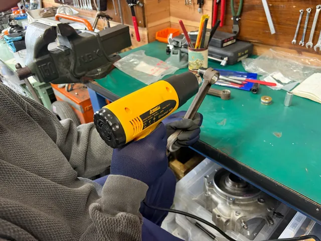 ヒートガンでコンロッドスモールエンドを加熱し、新品ブッシュの圧入を準備する作業